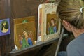 Under supervision of a monk a student is busy painting an icon