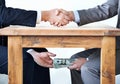 Under-the-table transactions.... Cropped shot of two businessmen shaking hands while money passes hands under a table. Royalty Free Stock Photo