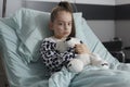 Under treatment ill little girl resting in pediatric healthcare facility while holding teddybear Royalty Free Stock Photo