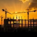 Under a vibrant orange sky with the sun partially hidden, several tall construction Royalty Free Stock Photo