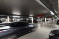 Underground parking garage with parked cars and a car passing by Royalty Free Stock Photo