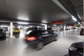 Underground parking garage with parked cars and a car passing by Royalty Free Stock Photo