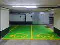 Underground parking spaces reserved for electric vehicles only. Small wall mounted charging plugs, green painted cement floor, no Royalty Free Stock Photo