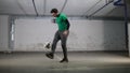 Underground parking. A young deft soccer man training football tricks. Kicking the ball