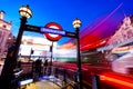 Underground sign, red bus in motion on Piccadilly Circus. London, UK at night Royalty Free Stock Photo