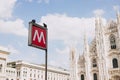 An underground subway metro tube traffic sign in Milan, Italy. sign metro station with blurred Milan Cathedral church Royalty Free Stock Photo