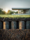 Underground view of soil layers and foundation piles supporting a modern house with grass-covered ground and sunset in the Royalty Free Stock Photo