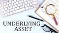 UNDERLYING ASSET text on blue background with keyboard and clipboard, business concept Royalty Free Stock Photo