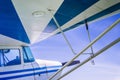Underneath wing of blue and white striped small vintage aircraft with sunny blue sky. Royalty Free Stock Photo