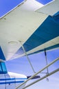 Underneath wing of blue and white striped small vintage aircraft with sunny blue sky. Royalty Free Stock Photo