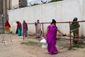Underprivileged women in sarees stand in a ilne following the social distancing norms to collect food rations at a