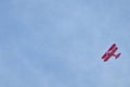 Undershot of a red biplane flying in the blue sky Royalty Free Stock Photo