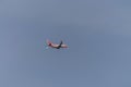 Underside view of a commercial airliner flying, blue sky as background