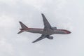 Underside view of a commercial airliner flying, blue sky as background