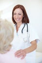 She understands that every patient needs her comforting attention. Friendly mature nurse comforts her elderly patient