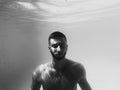 Underwater black and white portrait of man in swimming pool.