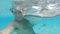 UNDERWATER: Cheerful man smiles while taking a selfie with a friendly stingray.