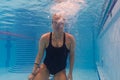 Underwater close-up of a young female swimmer surfacing in a bright pool, bubbles exploding around her face and goggles Royalty Free Stock Photo