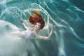 Underwater girl. Beautiful red-haired woman in a white dress, swimming under water. Royalty Free Stock Photo