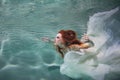 Underwater girl. Beautiful red-haired woman in a white dress, swimming under water. Royalty Free Stock Photo