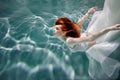 Underwater girl. Beautiful red-haired woman in a white dress, swimming under water.