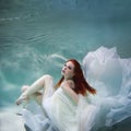 Underwater Girl. Beautiful Red-haired Woman In A White Dress, Swimming Under Water.