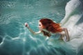 Underwater girl. Beautiful red-haired woman in a white dress, swimming under water. Royalty Free Stock Photo