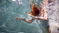 Underwater girl. Beautiful red-haired woman in a white dress, swimming under water. Royalty Free Stock Photo