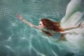 Underwater girl. Beautiful red-haired woman in a white dress, swimming under water. Royalty Free Stock Photo