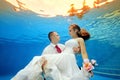 Underwater love a man holding his bride in a wedding dress on the background of a tropical sunset and looks at her Royalty Free Stock Photo