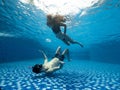 Underwater maternity photoshoot of a young pregnant couple in the swimming pool