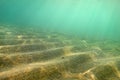 Underwater photo, small sand `dunes ` shot diagonally so in this perspective they form stairs, sun rays coming from sea surface. A Royalty Free Stock Photo