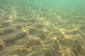 Underwater photo, sun shining on sea floor in shallow water, sand forming Royalty Free Stock Photo