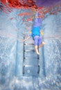 Underwater photo of young boy climbing out of swimming pool Royalty Free Stock Photo