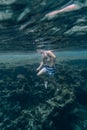 Underwater photograph of a man, boy, swimming among the rocks in the sea off the coast of Menorca