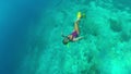 Underwater shooting of girls snorkeling deep into the blue water of the ocean, one girl reaches the bottom