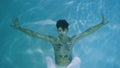 Underwater shot of man with a halfnaked torso gracefully dancing modern ballet choreography. Male dancer moves in blue