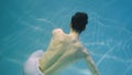 Underwater shot of man with a halfnaked torso gracefully dancing modern ballet choreography. Male dancer moves in blue