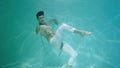 Underwater shot of man with a halfnaked torso wrapped in chains dancing modern ballet choreography. Male dancer moves in