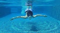 Underwater shot of young woman diving into the swimming pool Royalty Free Stock Photo