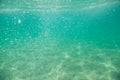 Underwater. Sun glare at the bottom of the seat. Waves underwater and rays of sunlight shining through. Deep turquoise blue sea.