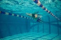 Underwater swimmer gliding beneath surface in pool lane marked with blue and red float dividers Royalty Free Stock Photo