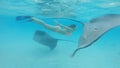 UNDERWATER: Two gentle stingrays swim around happy woman diving in the ocean.