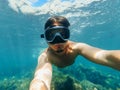 Underwater view of a diver man swimming in the turquoise sea under the surface with snorkelling mask taking a selfie Royalty Free Stock Photo