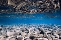 Underwater view with stones bottom, reflection in sea water. Ocean background