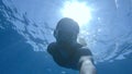 UNDERWATER: Young male diver swims down into the depths of the glassy ocean. Royalty Free Stock Photo