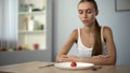 Underweight woman looking at small portion of meal, exhausted body, severe diets