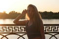 Undisturbed blond haired lady posing leaning at fence by hand in sunset light full of lovesikness