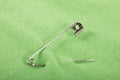 Undo safety pin halfway fastened on a green cloth Royalty Free Stock Photo