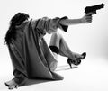 Undressed girl sits back and aims with handgun